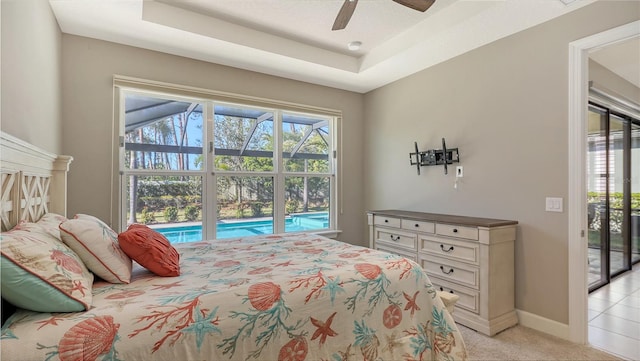 carpeted bedroom with ceiling fan, access to outside, and a tray ceiling