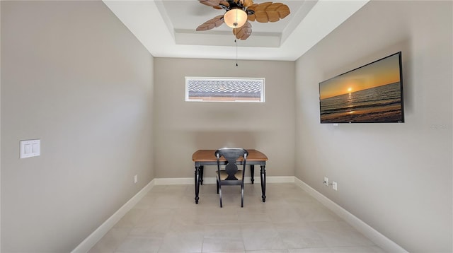 office area with a raised ceiling and ceiling fan