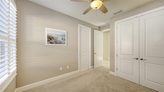 unfurnished bedroom featuring ceiling fan, light colored carpet, and multiple windows