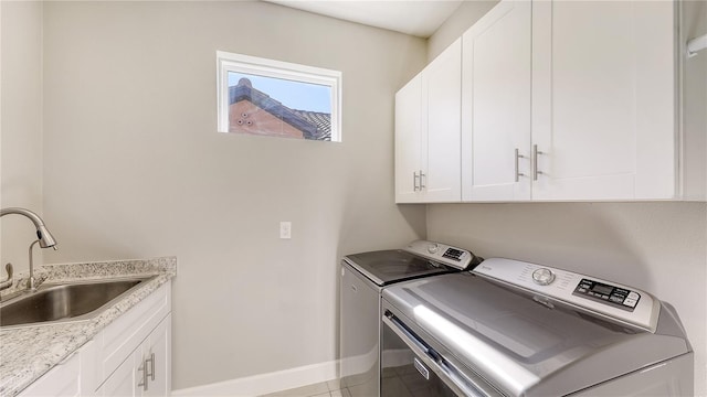 laundry area featuring cabinets, light tile patterned floors, washing machine and dryer, and sink