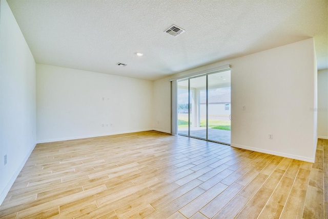 unfurnished room featuring light hardwood / wood-style floors and a textured ceiling