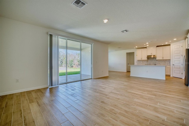 unfurnished living room featuring a textured ceiling and light hardwood / wood-style flooring