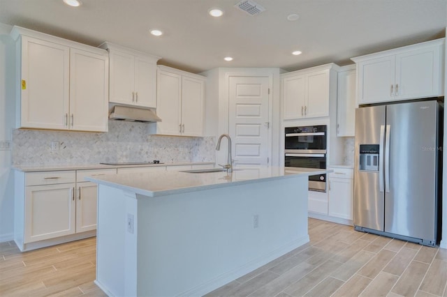 kitchen with white cabinets, appliances with stainless steel finishes, and a center island with sink