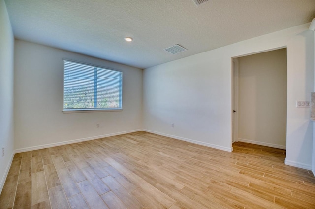 empty room with light hardwood / wood-style flooring and a textured ceiling