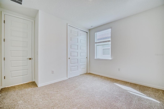 unfurnished bedroom featuring carpet floors, a textured ceiling, and a closet