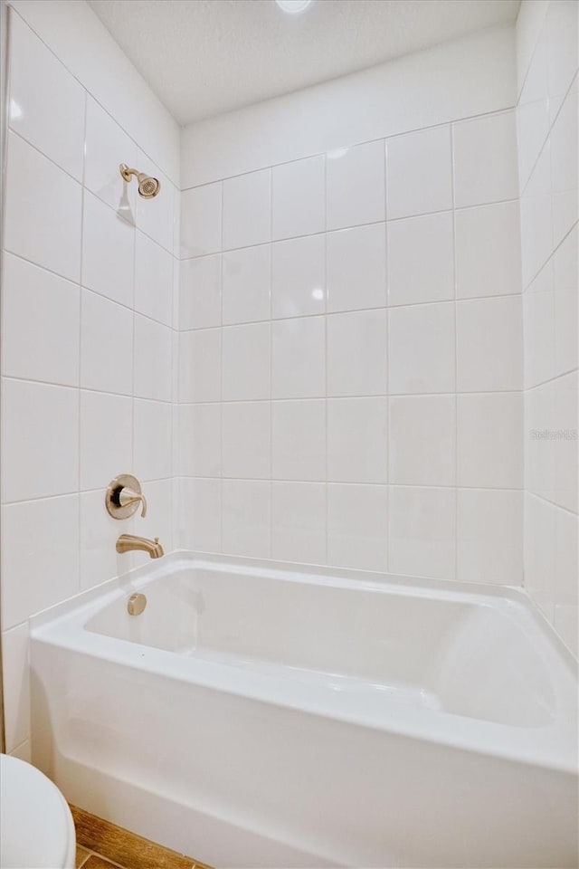 bathroom with toilet and tiled shower / bath