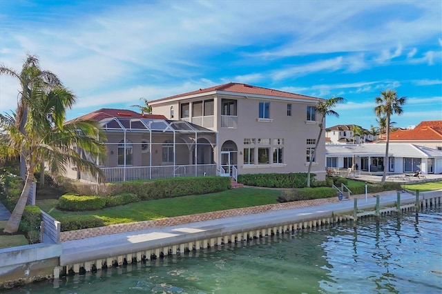 back of property with stucco siding, a yard, and a water view