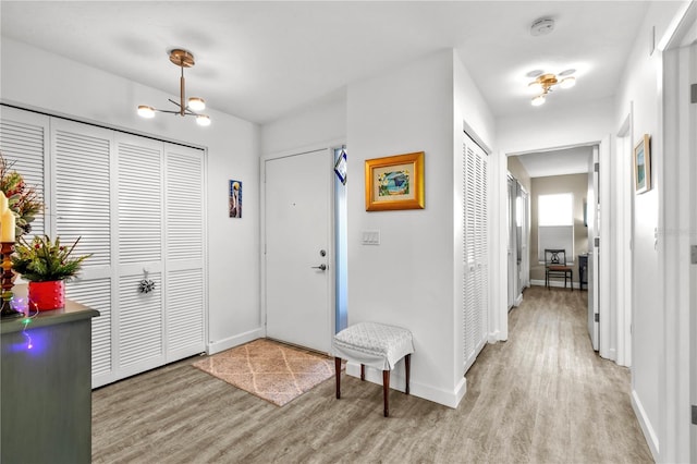 foyer entrance with light wood-type flooring and an inviting chandelier