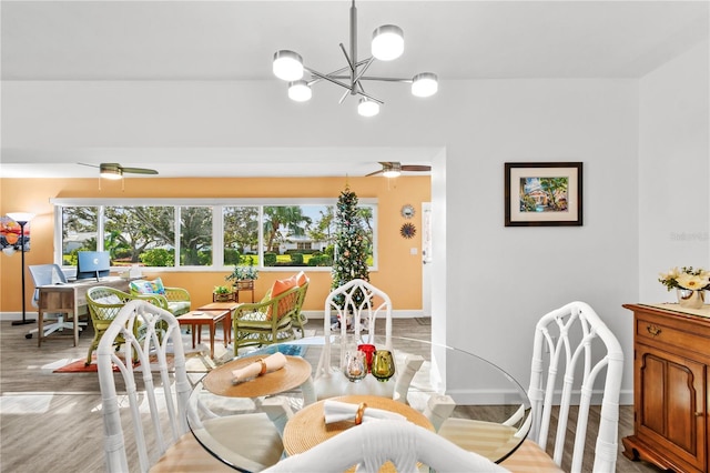 dining space with ceiling fan with notable chandelier and light wood-type flooring