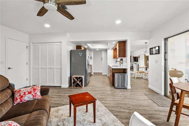 living room with ceiling fan, sink, and light hardwood / wood-style floors