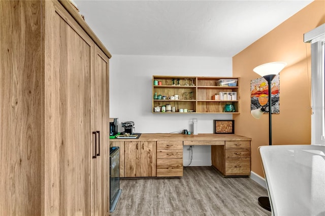 office space featuring built in desk and light hardwood / wood-style flooring