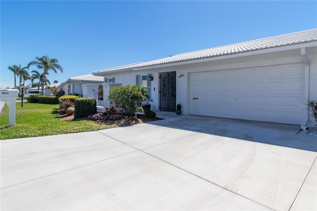 ranch-style house with concrete driveway, a tiled roof, a garage, and stucco siding