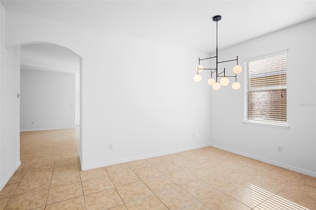 tiled spare room featuring an inviting chandelier