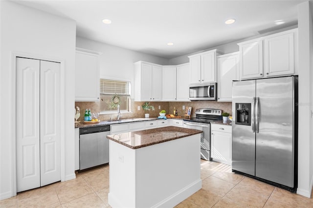 kitchen featuring a kitchen island, appliances with stainless steel finishes, sink, white cabinets, and dark stone counters