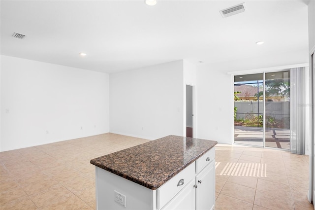 kitchen with white cabinetry, a center island, dark stone countertops, and light tile patterned flooring