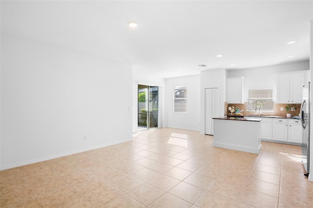 kitchen featuring tasteful backsplash, white cabinetry, sink, and light tile patterned floors