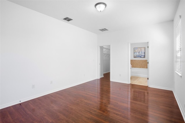 unfurnished bedroom featuring hardwood / wood-style floors, a walk in closet, a closet, and ensuite bathroom