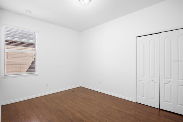 unfurnished bedroom featuring dark hardwood / wood-style flooring and a closet