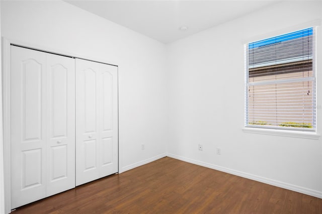 unfurnished bedroom featuring dark hardwood / wood-style flooring and a closet