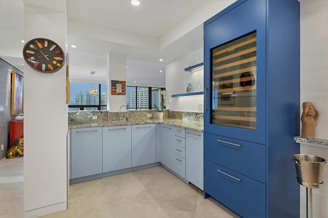 kitchen with blue cabinets, light stone countertops, and sink