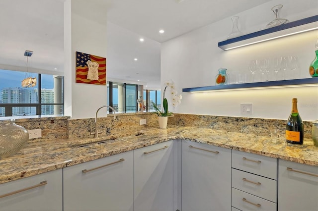 kitchen featuring white cabinetry, sink, light stone counters, and decorative light fixtures