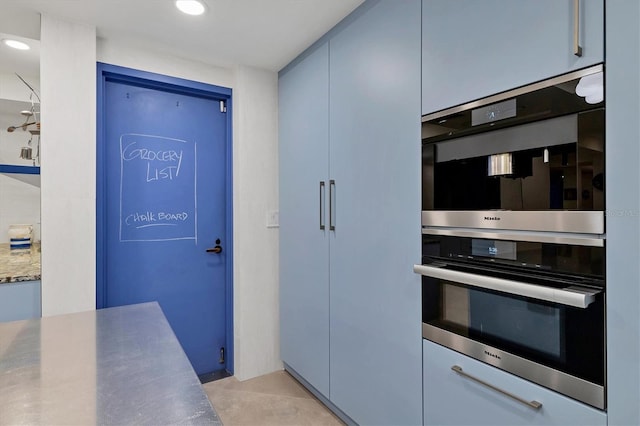 kitchen with light tile patterned floors, stainless steel double oven, and blue cabinets