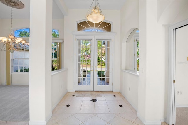 doorway to outside with french doors, light tile patterned flooring, high vaulted ceiling, and an inviting chandelier