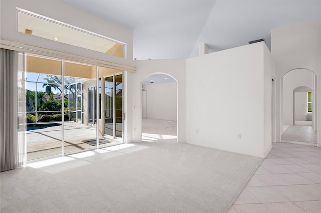 empty room featuring light tile patterned flooring and high vaulted ceiling