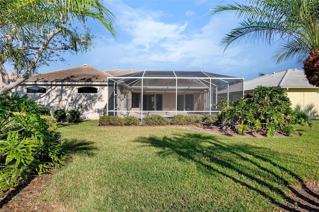 back of property with a lawn and glass enclosure