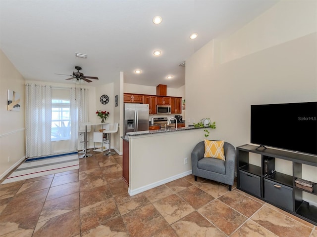 kitchen featuring kitchen peninsula, appliances with stainless steel finishes, ceiling fan, sink, and dark stone countertops