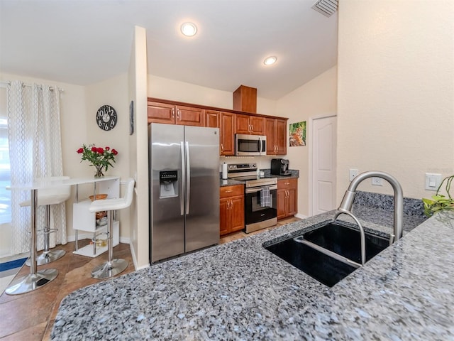 kitchen with light stone countertops, stainless steel appliances, tile patterned floors, and sink