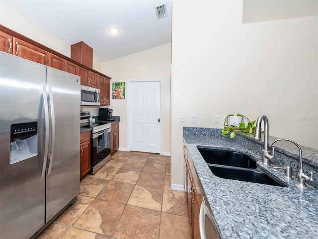 kitchen with light stone countertops, sink, vaulted ceiling, and appliances with stainless steel finishes