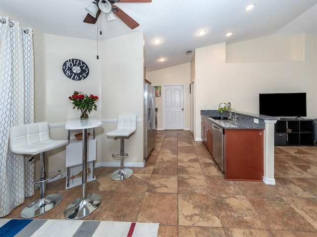 kitchen with sink, a kitchen bar, stainless steel appliances, and vaulted ceiling