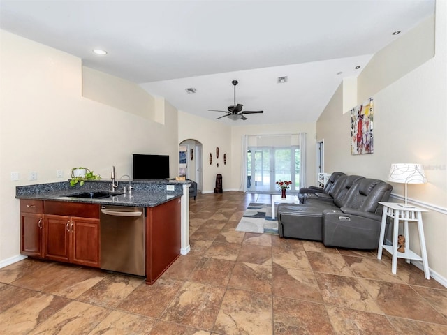 kitchen featuring ceiling fan, dishwasher, sink, dark stone counters, and vaulted ceiling