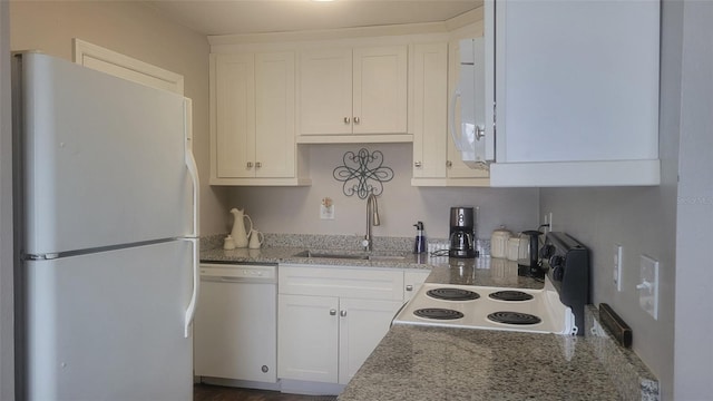 kitchen with white cabinetry, light stone countertops, white appliances, and sink