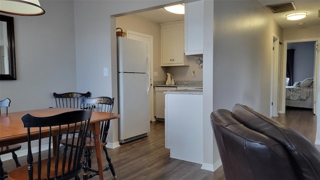 kitchen with white cabinets, white appliances, and dark hardwood / wood-style floors