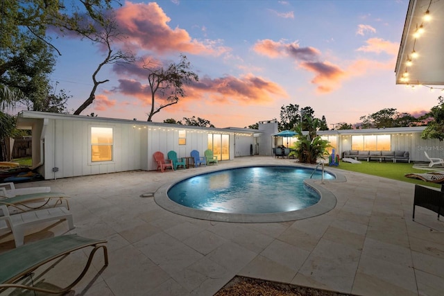 pool at dusk featuring a patio