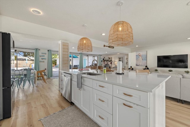 kitchen featuring sink, decorative light fixtures, dishwasher, an island with sink, and white cabinets