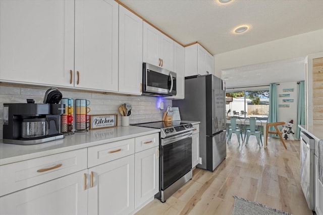 kitchen featuring a textured ceiling, appliances with stainless steel finishes, light hardwood / wood-style floors, decorative backsplash, and white cabinets