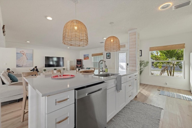 kitchen with dishwasher, an island with sink, sink, white cabinets, and hanging light fixtures