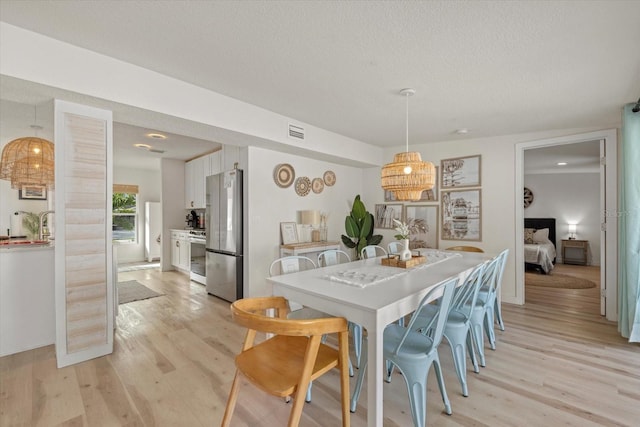 dining room featuring light hardwood / wood-style flooring and a textured ceiling