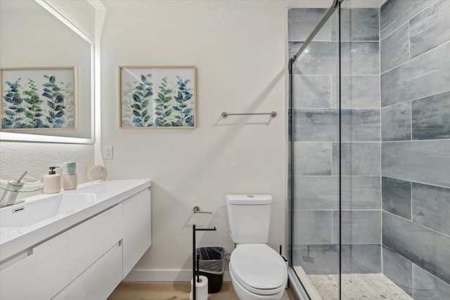 bathroom featuring a shower with door, vanity, hardwood / wood-style flooring, and toilet