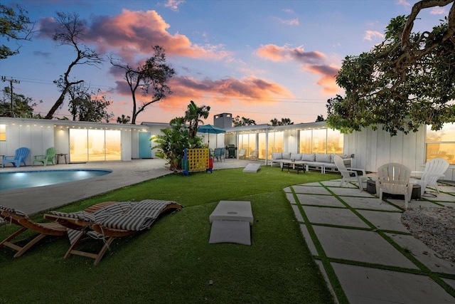 yard at dusk with an outdoor living space and a patio