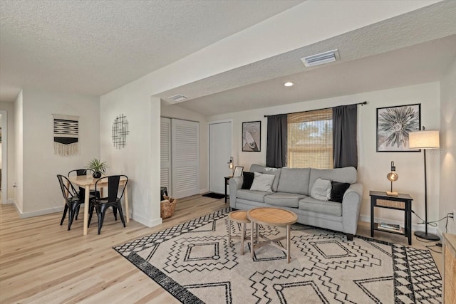 living room featuring light hardwood / wood-style flooring and a textured ceiling