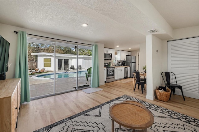 living room with sink, light hardwood / wood-style floors, and a textured ceiling