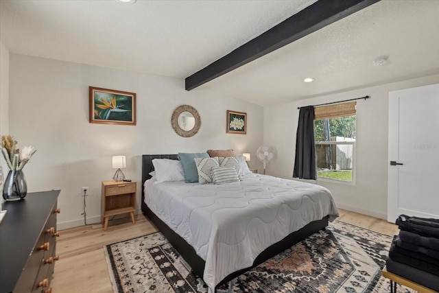 bedroom featuring beamed ceiling, a textured ceiling, and light wood-type flooring