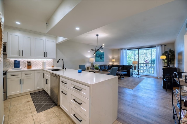 kitchen featuring white cabinets, sink, kitchen peninsula, and stainless steel appliances