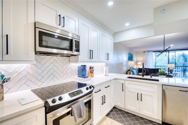 kitchen with white cabinets, sink, appliances with stainless steel finishes, tasteful backsplash, and kitchen peninsula