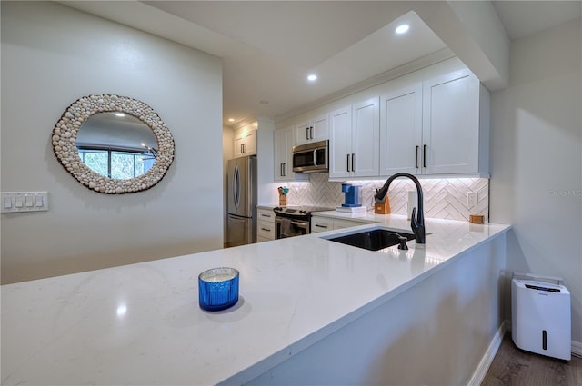 kitchen with white cabinets, sink, decorative backsplash, wood-type flooring, and stainless steel appliances