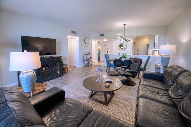 living room with light wood-type flooring and a notable chandelier